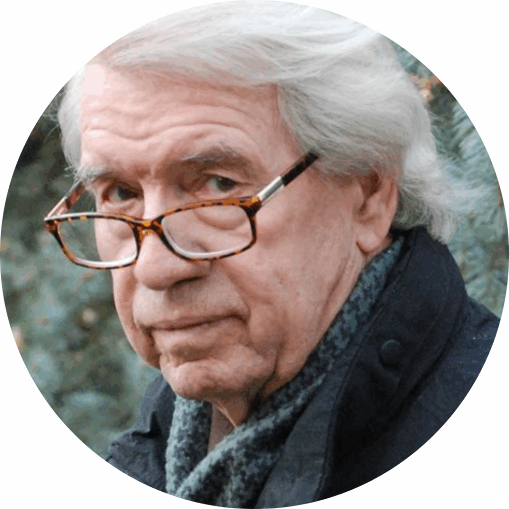 Headshot of Emmy Award-winning film producer, Brian Doubleday with white hair, brown eyes and brown, tortoiseshell reading glasses wearing a green patterned shirt, and a black jacket in front of a pine tree background.